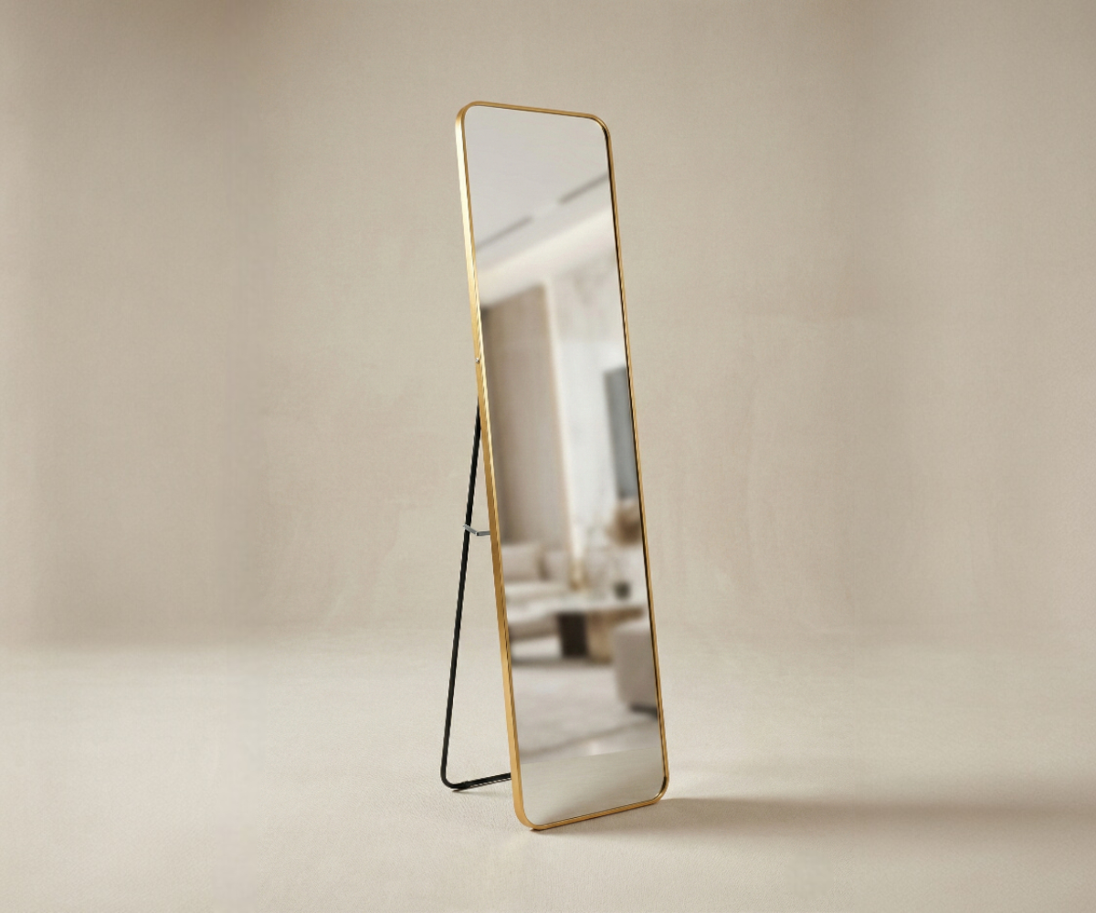 058 gold standing mirror in a warm-lit bedroom with an armchair