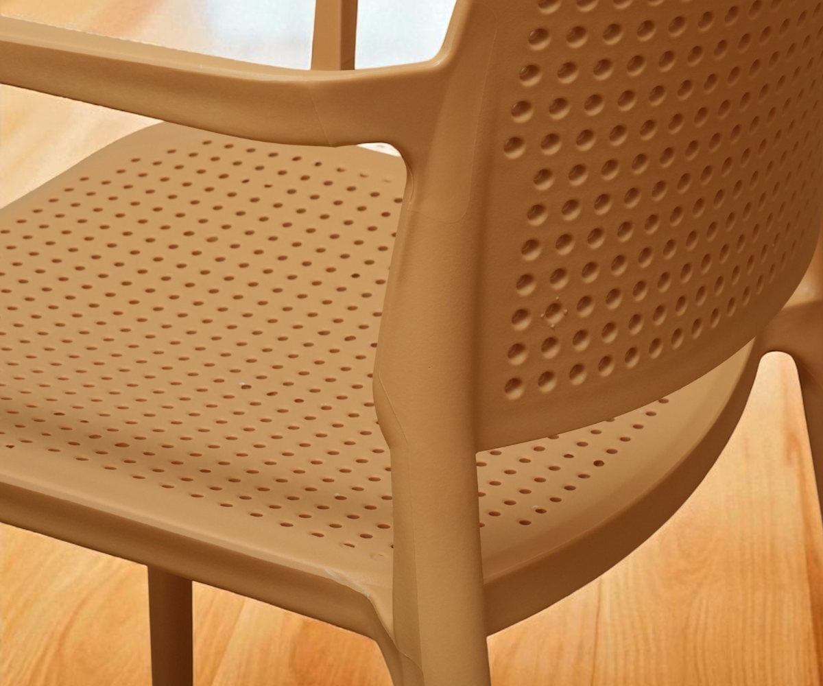 8339A perforated outdoor armchair in beige, angled view on a wood floor