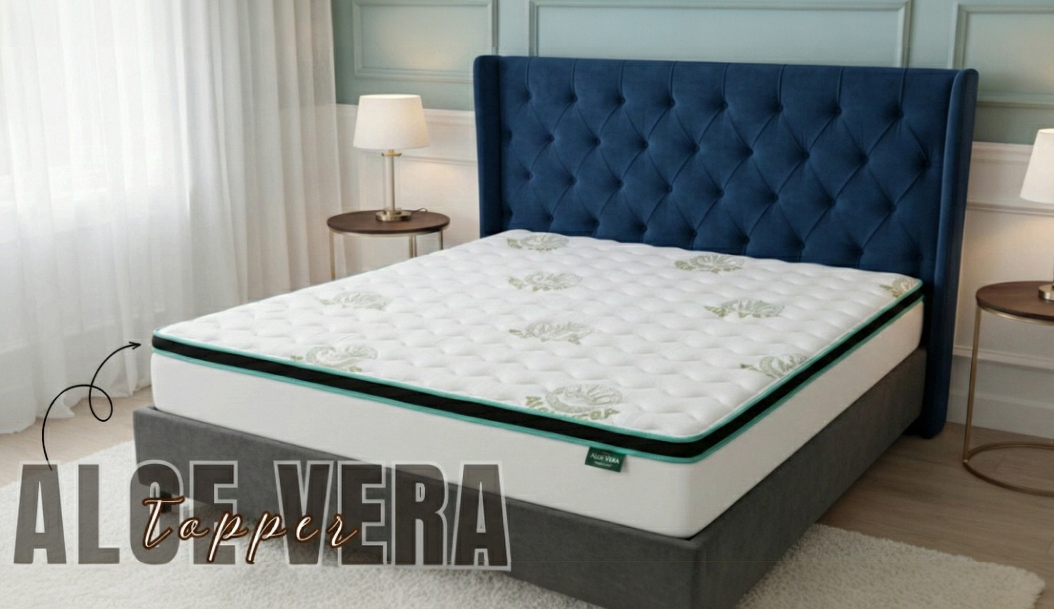 Aloe Vera mattress with a green leaf-print border, on a grey bed base with a navy tufted headboard