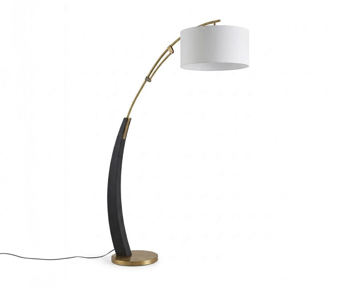 Black and gold arc floor lamp with white drum shade styled beside a sofa in a luxurious, well-lit modern living room