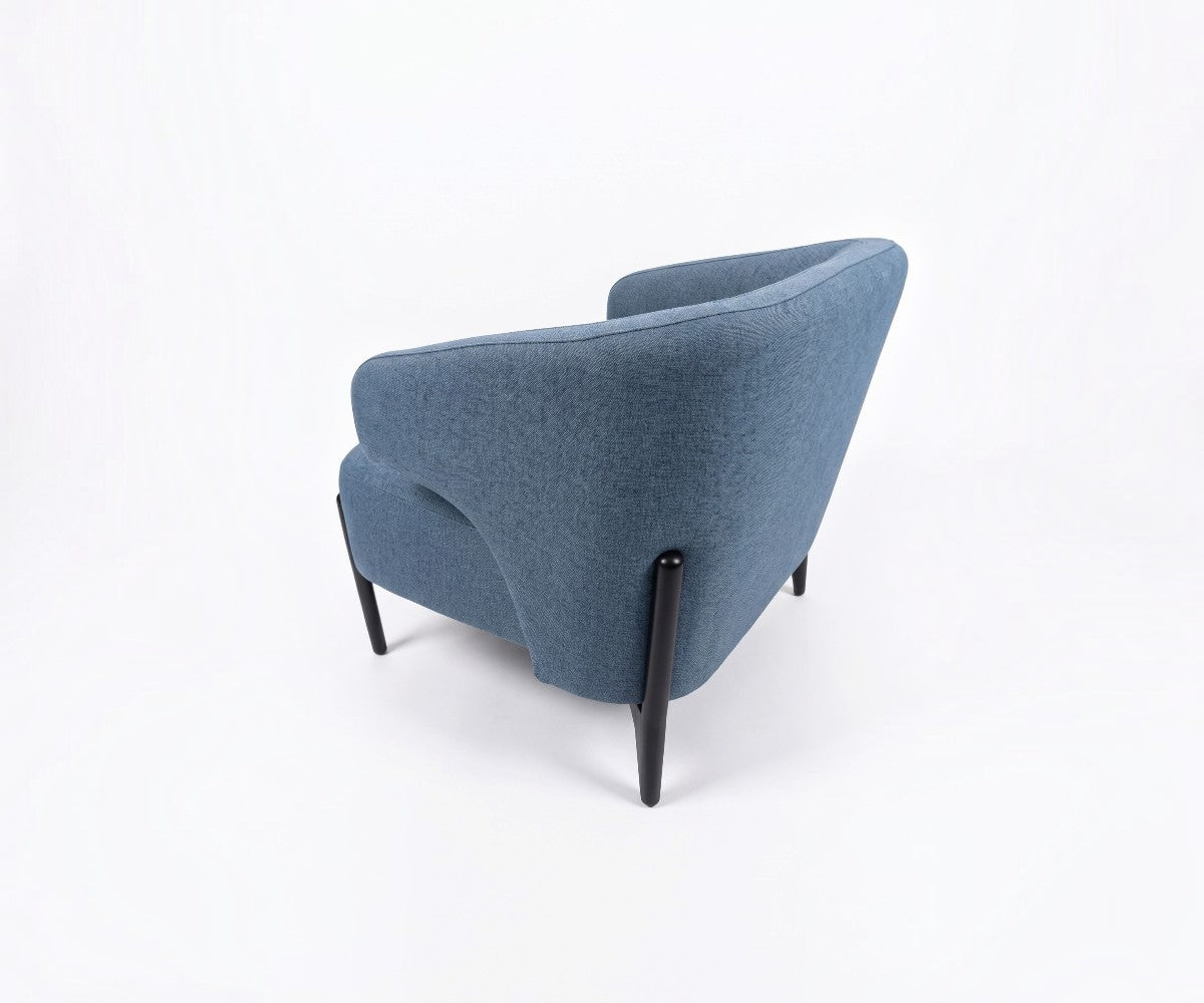 Blue accent armchair with curved backrest styled in a luxurious, well-lit modern living room