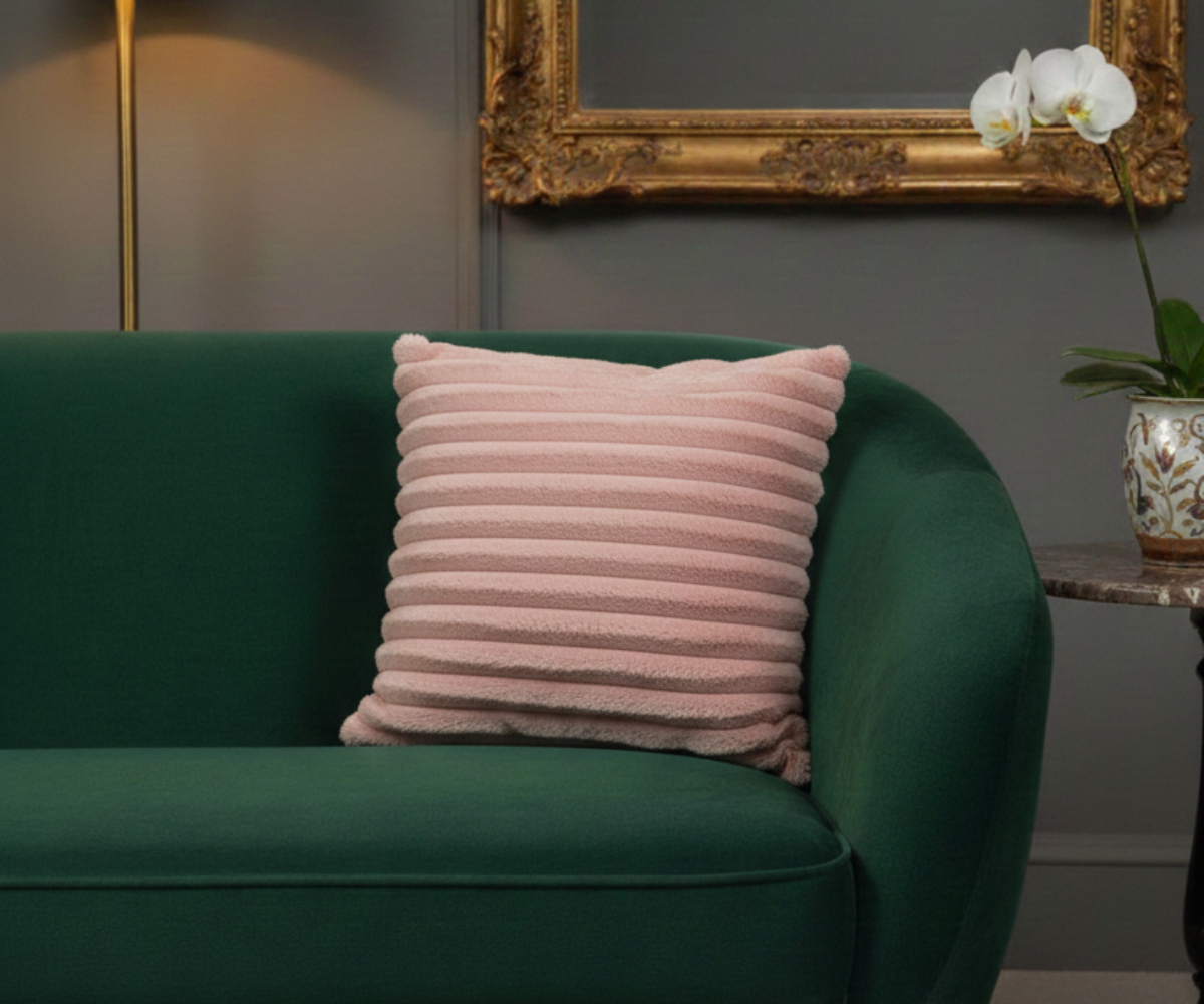 Blush ribbed velvet cushion cover on a green sofa in a grey panelled room