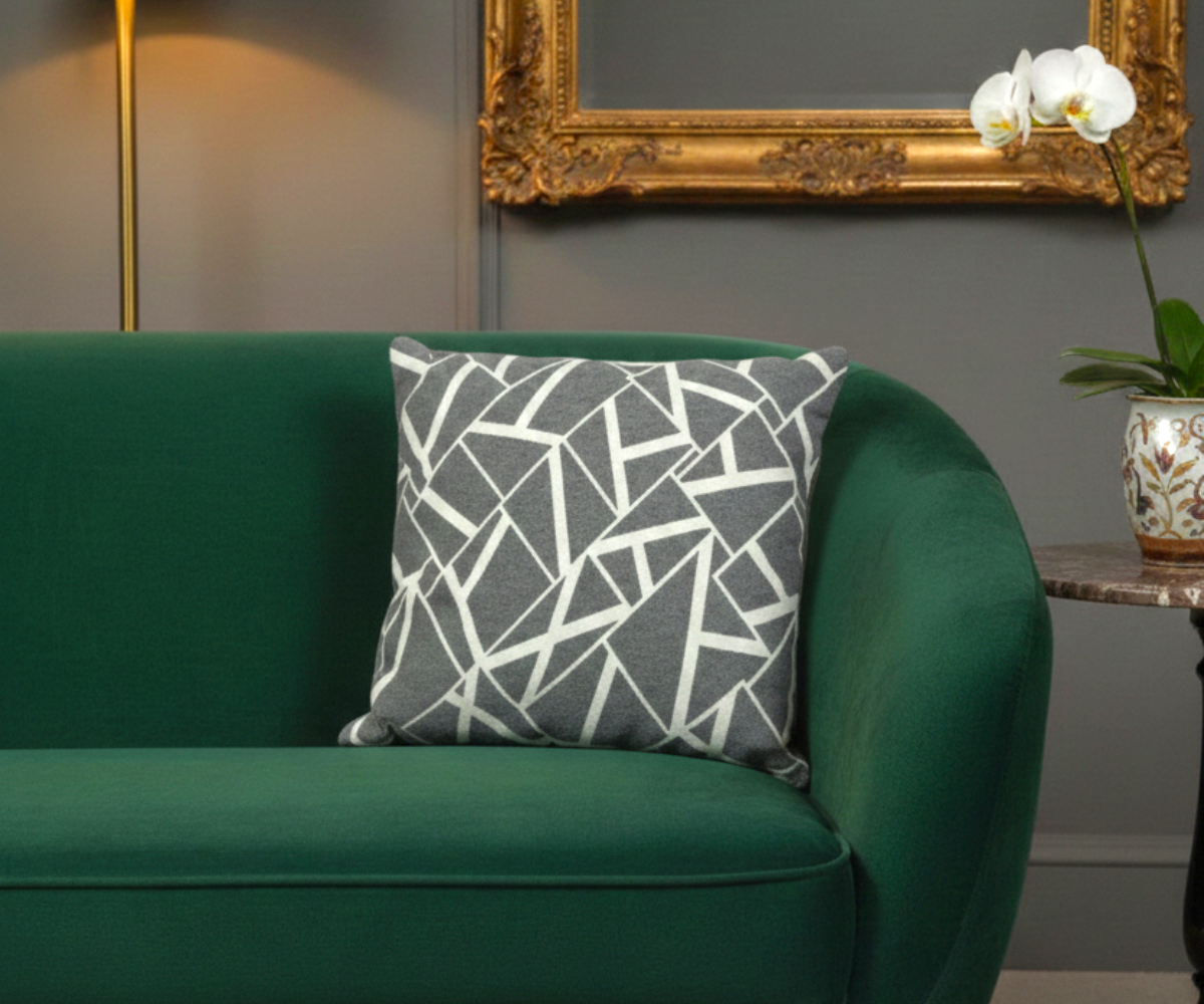 Charcoal abstract geo cushion cover on a green sofa in a grey room