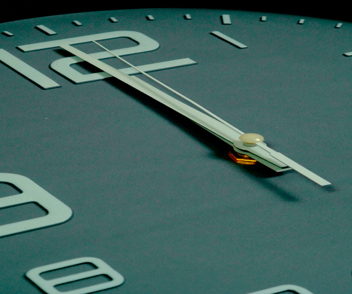Deep teal outline numeral wall clock with a cream rim on a pale ground