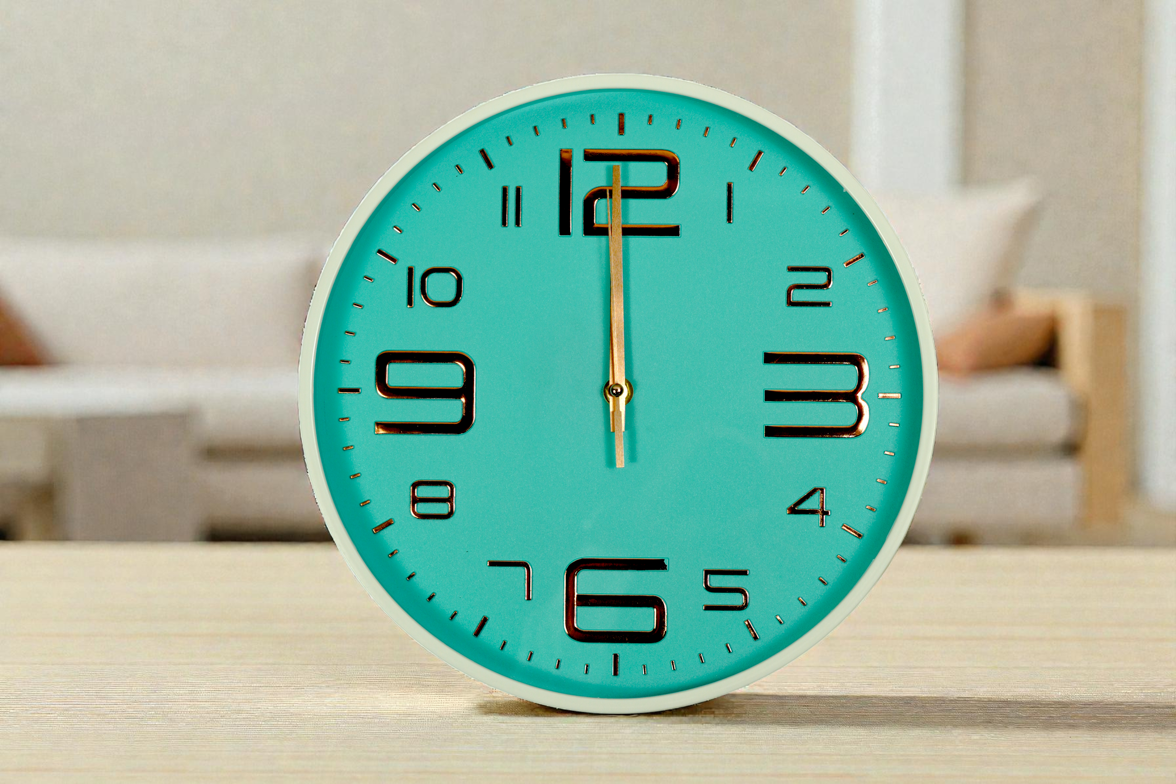 Mint gold numeral wall clock on a wooden shelf in a bright living room