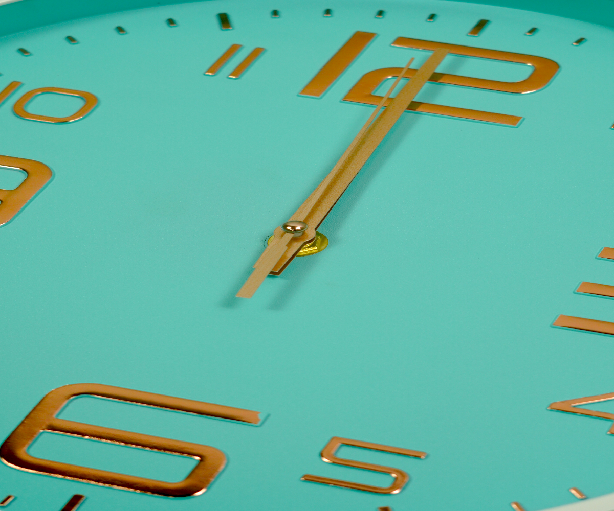 Mint gold numeral wall clock on a wooden shelf in a bright living room
