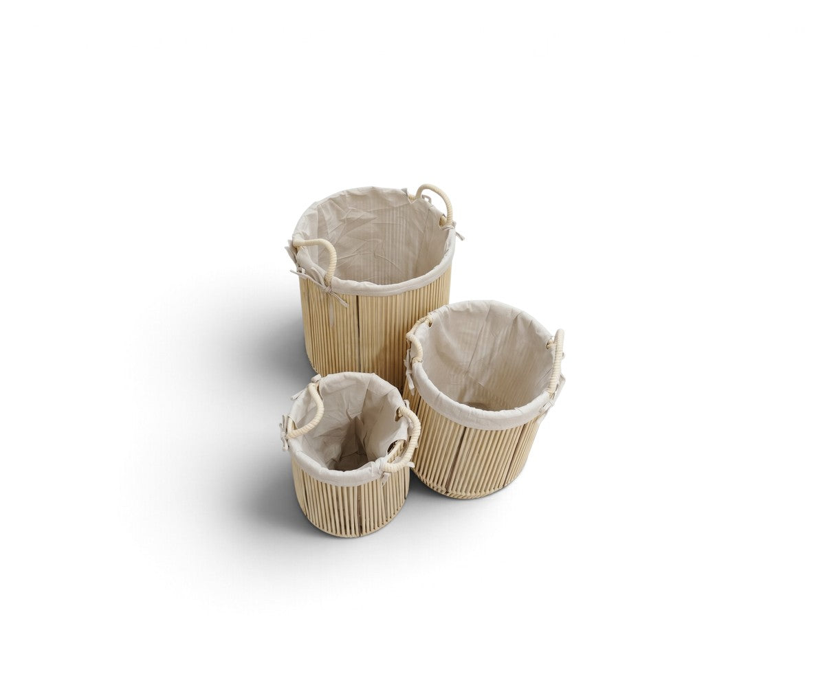 Natural three-piece round laundry basket set with cream lining and handles styled in a luxurious, well-lit modern dressing room