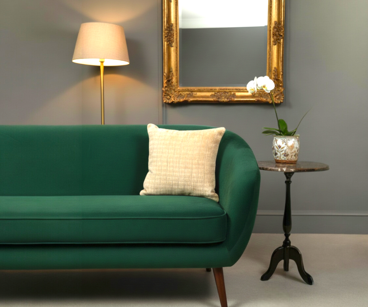 Natural woven linen cushion cover on a green sofa in a grey room