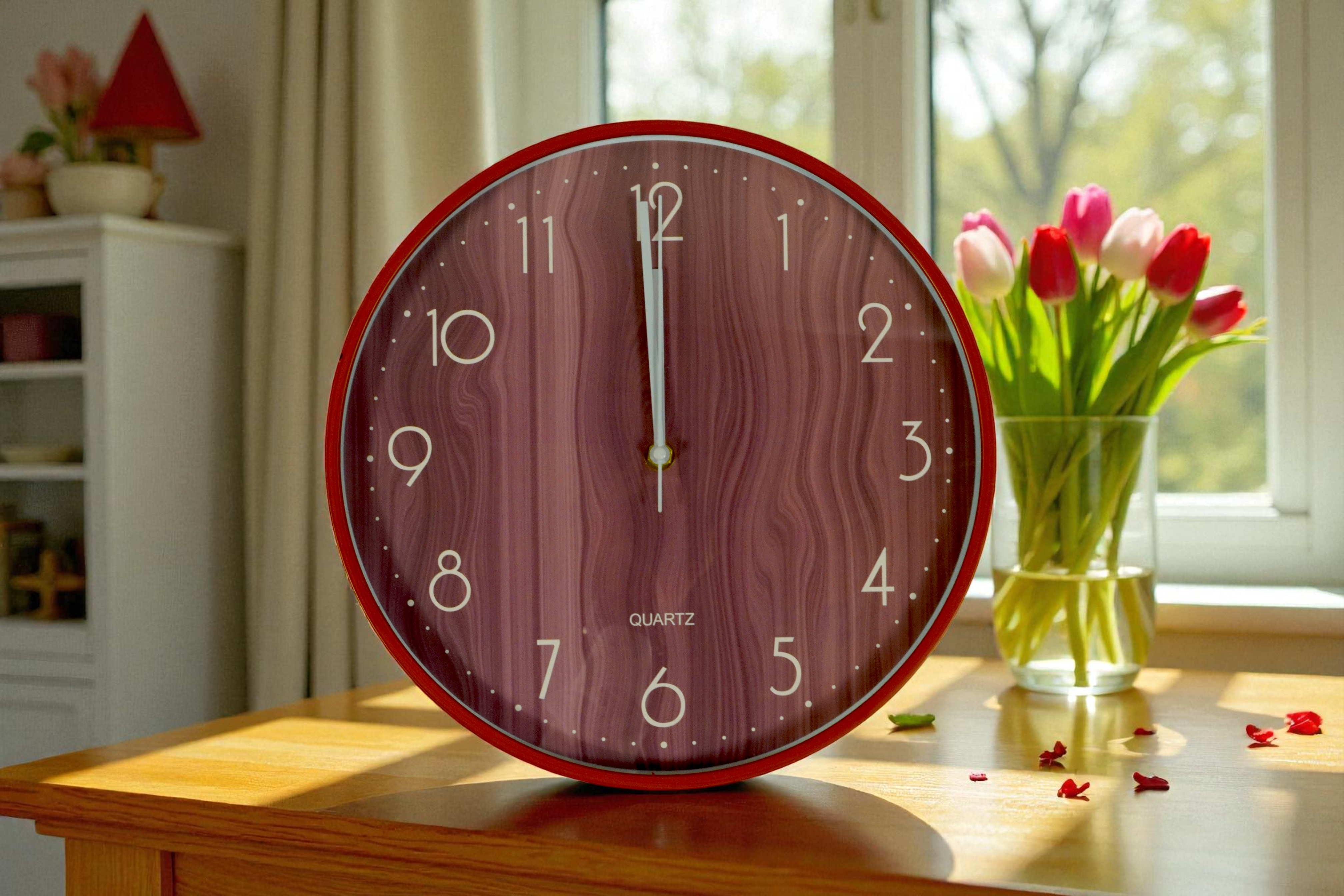 Red rim woodgrain wall clock on a sideboard beside pink tulips