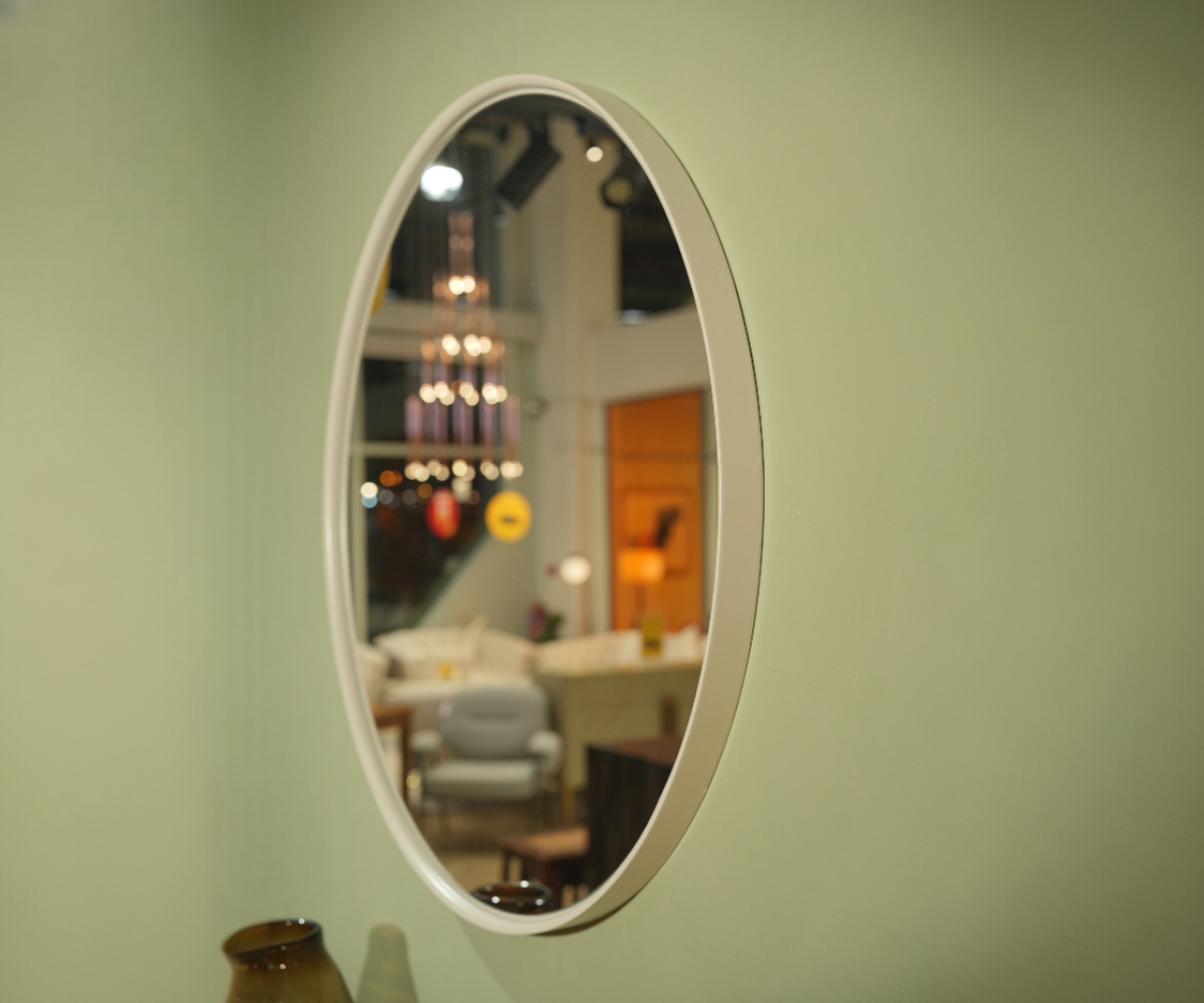 Round modern wall mirror on a sage wall above a walnut console table