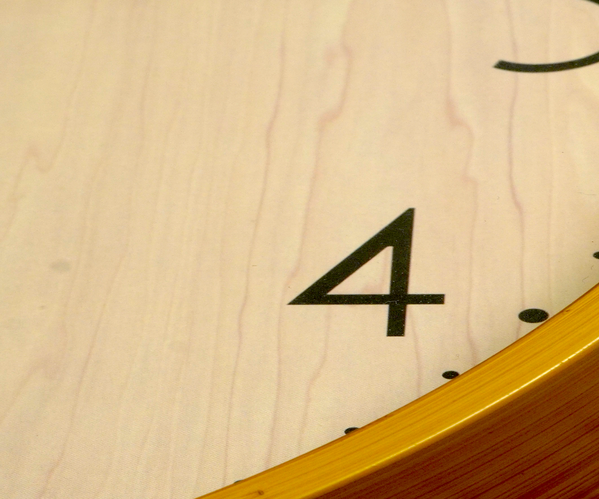 Wall Street natural wood wall clock on a cream wall beside a throw
